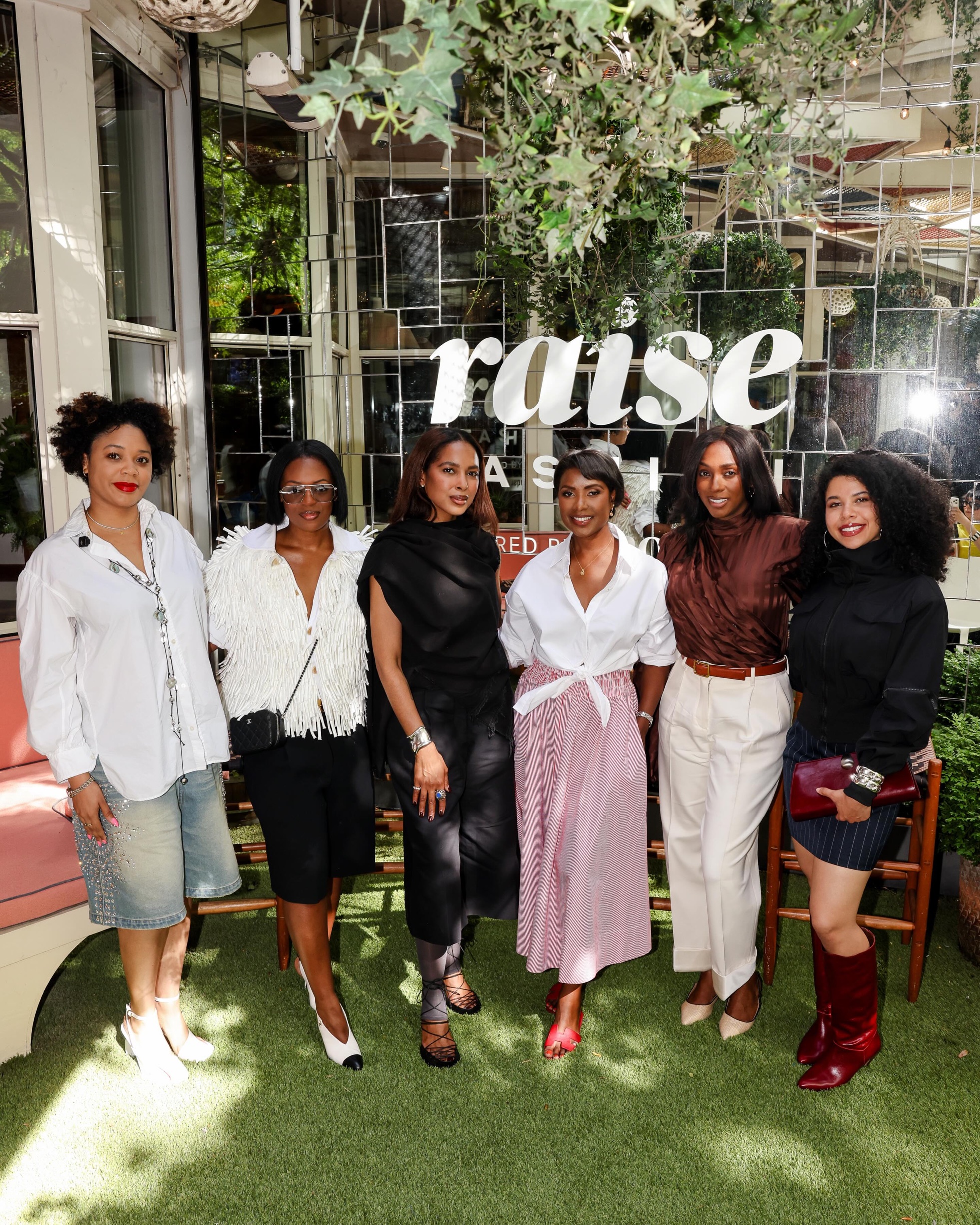 Group of six at a RAISE Fashion event in front of the RAISE sign, makeup by Rebecca Lee Artistry